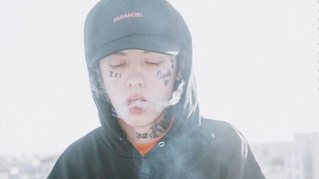 Lil Xan puhaltaa savua ulos suusta silmät kiinni.