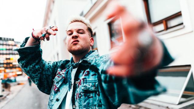Lukas Leon poseeraa käsimerkkien kanssa.