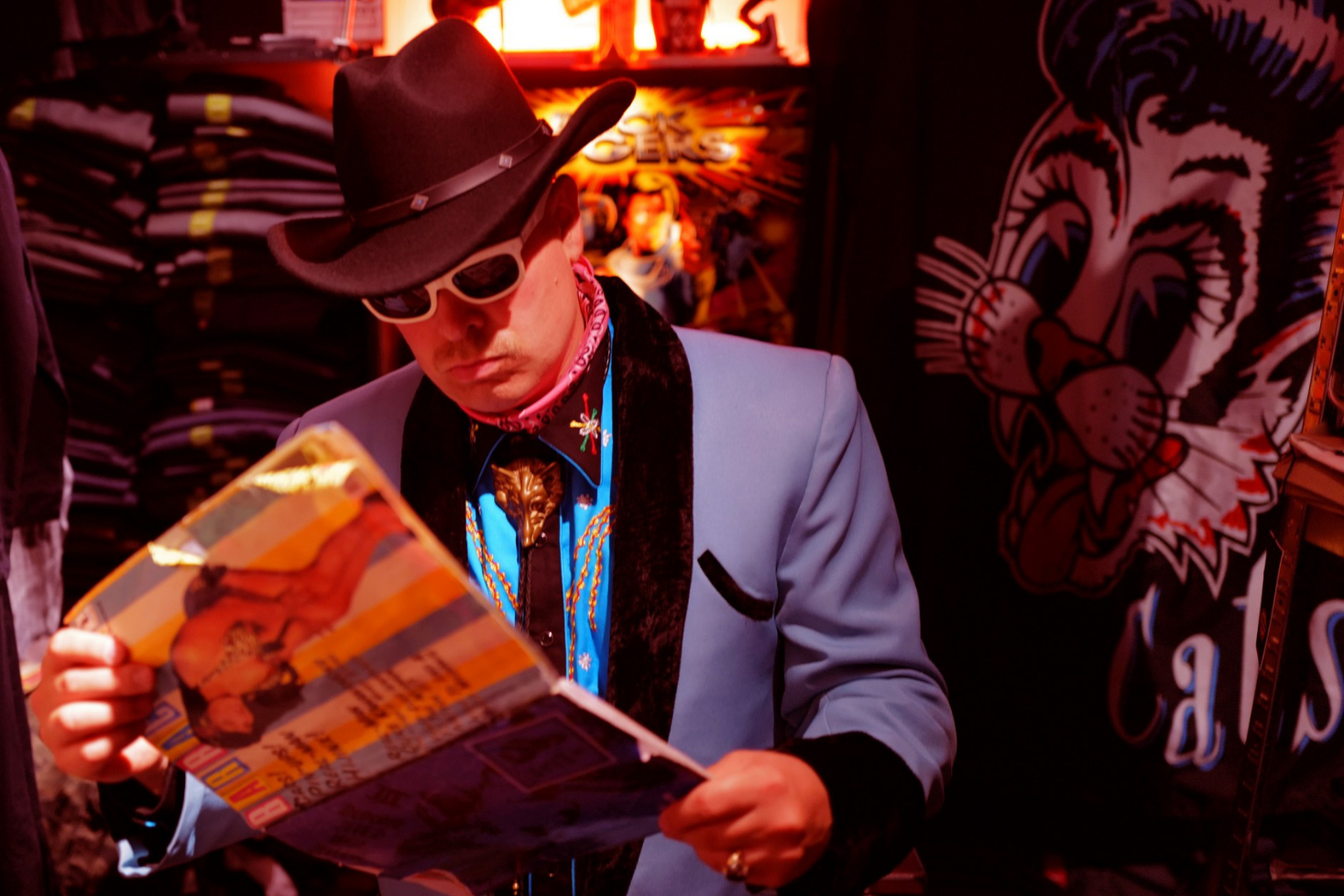 Heikki Kuula katsoo lehteä cowboy-henkinen asu päällä.