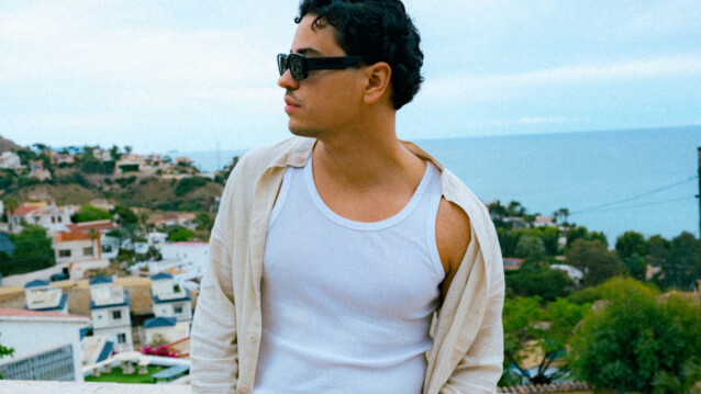 Karim B poseeraa parvekkeella marokkolainen kaupunkimaisema takanaan.