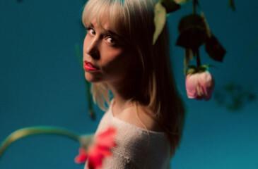 Ellis katsoo kameraa kohti kukkien keskellä.