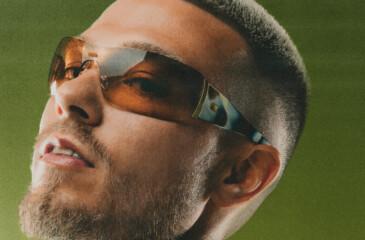 Yrjänä aurinkolasit päässä vihreää taustaa vasten.