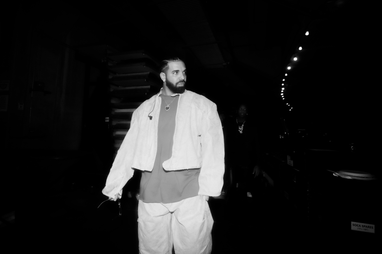 Drake kävelee lavan takana tummassa taustassa