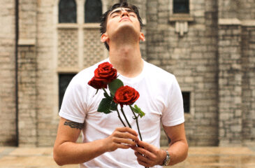 Robin Packalen katsoo ylös pitäen käsissään kahta punaista ruusua.