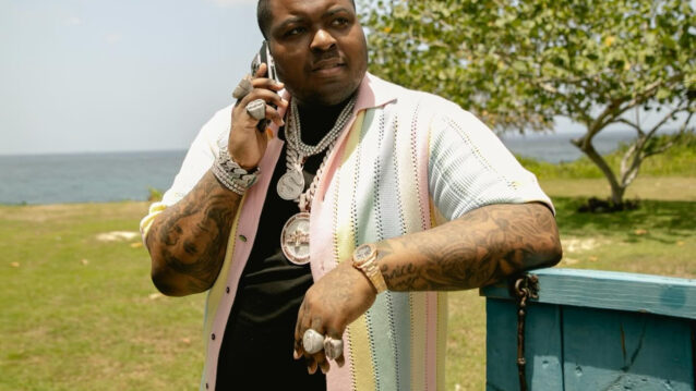 Sean Kingston nojaa puukylttiin puhuen samalla puhelimeen.