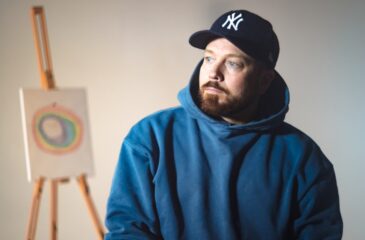 Pikku G lippis päässä, taulu takana