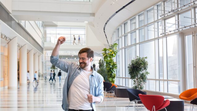 Mies heiluu kädet ilmassa. Musiikki parantaa työhyvinvointia!