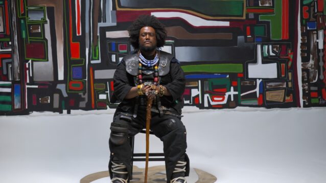 Kamasi Washington istuu tuolilla. Kamasi Washington palaa Suomeen!