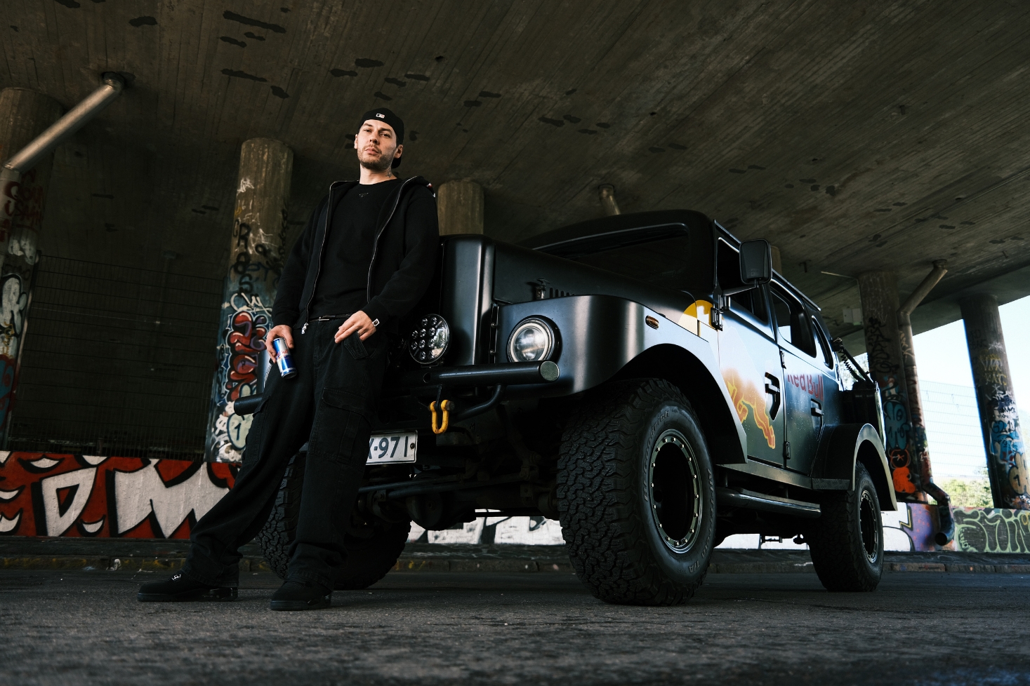 Kube nojaa autoa vasten. Red Bull Sana Sanasta palaa!