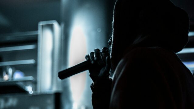 Henkilö mikrofoni kädessä. Rap on runoutta, mutta lyriikoiden naisvihamielisyys voi olla vaaraksi.