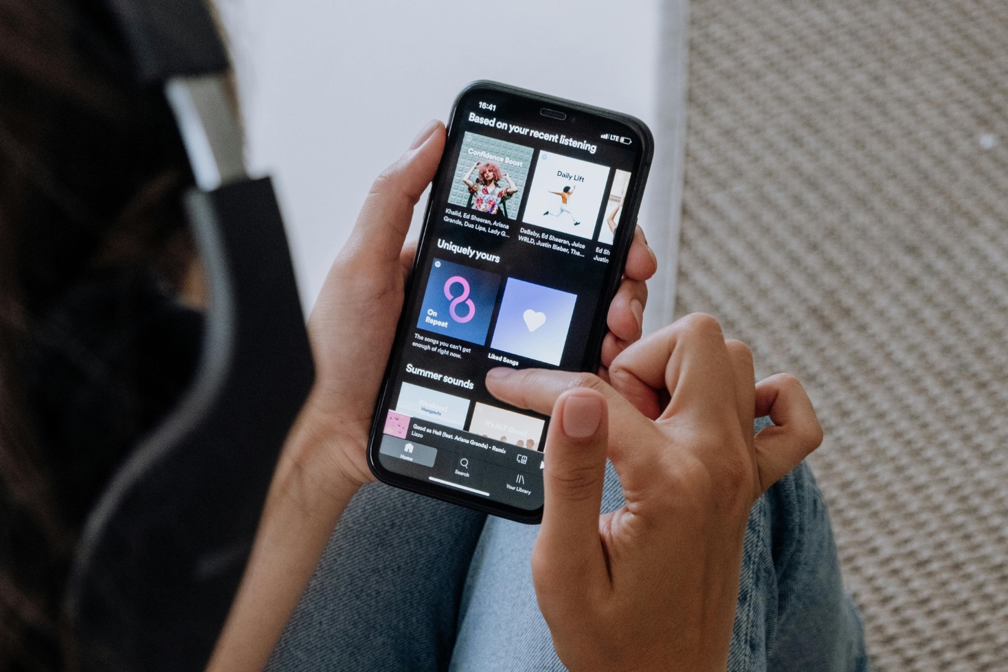 Henkilö selaa Spotify-suosituksia sovelluksesta puhelimella. Suomen Spotify-soittolistojen kuratointi siirtyy Ruotsiin