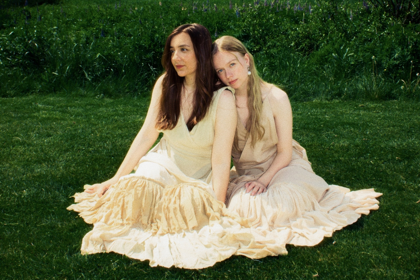 Emma & Matilda nurmikolla istumassa. Emma & Matilda esiintyvät Yle Kesäfestivaali 2026 -tapahtumassa!