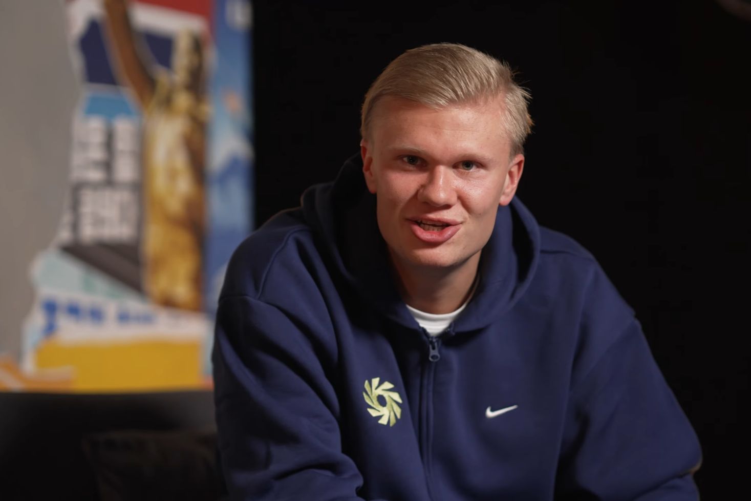 Erling Haaland, Call of Duty -camper, puhuu kameralle tummansinisessä hupparissa.