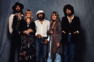 Fleetwood Mac -dokumentti: yhtyeen viisi jäsentä poseeraa harmaata kangastaustaa vasten 1970-luvun tyyliin pukeutuneina
