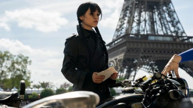 Jenna Ortega Wednesday Addamsina Eiffel-tornin edessä, Thing-käsi moottoripyörän ohjaustangolla