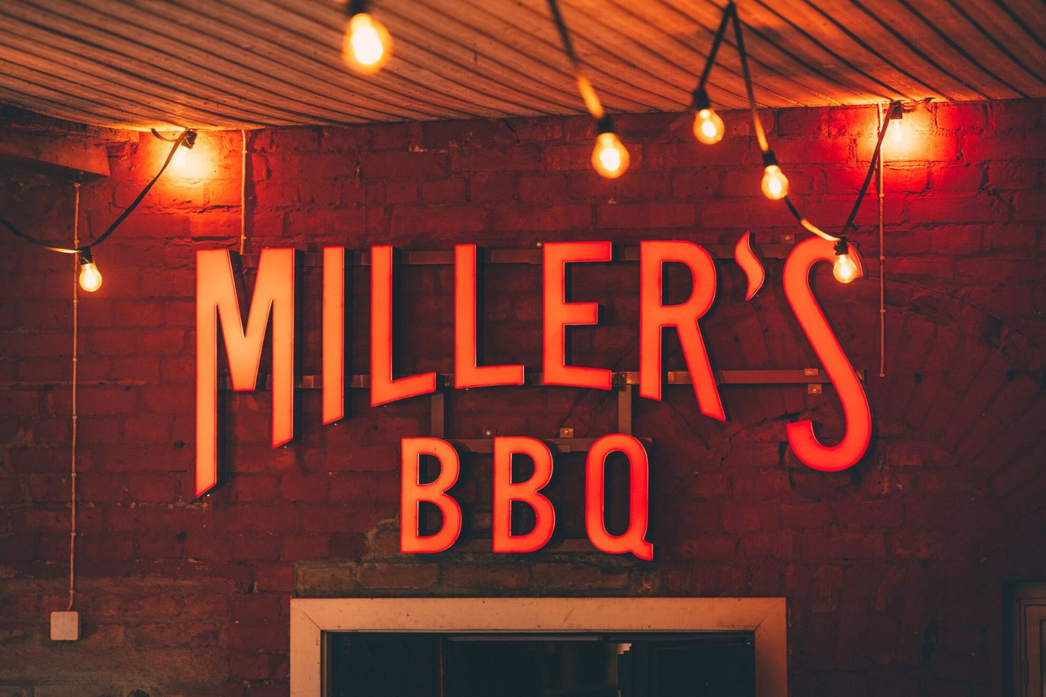 Miller’s BBQ Töölö -ravintolan valokyltti tiiliseinällä